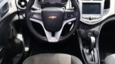 Front interior view of a Chevrolet car showing the steering wheel with logo, instrument cluster, center touchscreen, and climate controls.