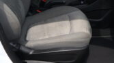 Front passenger seat area in a car, with red-release seat belt buckles and center console visible between seats.