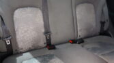 Gray car back seat with three seat cushions, patterned fabric, and visible three-point seatbelts with buckles on each seat.