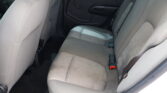 Gray fabric rear car seat with headrest and visible seat belts; interior door panel in view.