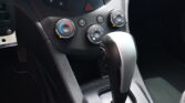 Close-up of a car dashboard showing climate control dials, hazard light button, and the gear lever with the parking brake nearby