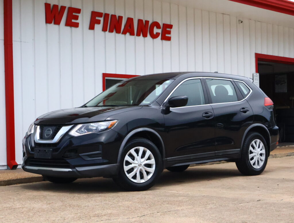 Gray Nissan SUV parked in front of a white building with red trim and a 'WE FINANCE' sign above the entrance.