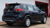 Rear three-quarter view of a black Nissan Rogue SUV parked in front of a white building with red trim doors and accents.