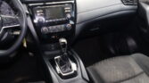 Interior of a car focusing on the center console: infotainment screen, climate controls, and gear shifter with black upholstery.