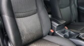 Black fabric car seats with a textured pattern and light contrast stitching, showing the front seating area and center console.