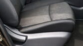 Black leather car seat with visible stitching, center console area, and a red seat belt buckle nearby.
