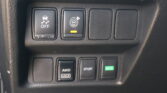 Close-up of a car's center console: left button shows traction control off with a car and wavy lines; middle button activates parking sensors with an orange indicator; two blank buttons to the right.