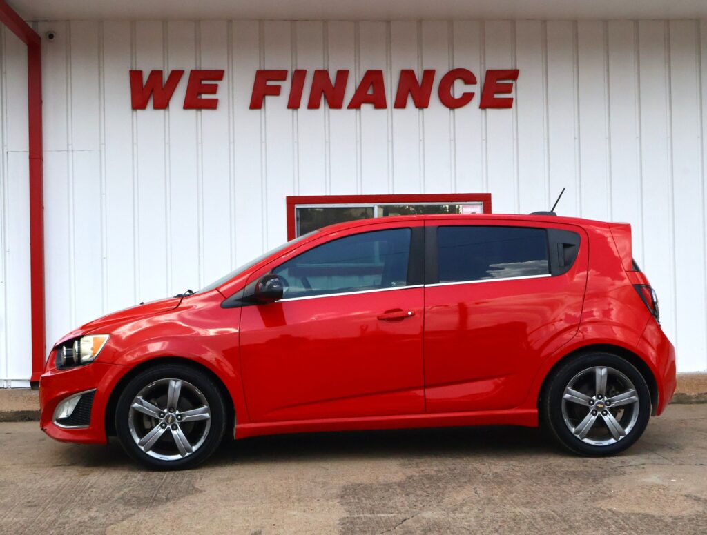 Red car parked in front of a white wall with large red letters saying WE FINANCE