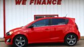 Red car parked in front of a white wall with large red letters saying WE FINANCE