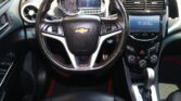 Interior view of a car dashboard centered on the black leather steering wheel with Chevrolet emblem, digital instrument cluster, and center console display.