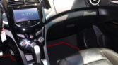 Interior of a car showing the center touchscreen, climate controls, and gear shifter with a glossy black dashboard surface and passenger-side circular air vent.