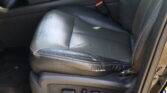 Black leather car seat with visible wear and scratches, side adjustment controls in foreground.
