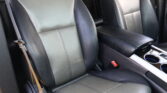 Front car seats in black leather with light stitching and a center console with cupholders visible between them, inside a vehicle interior.