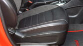 Black leather car interior with red contrast stitching, showing the driver/passenger seat, center console, gear shifter, and red exterior edge on the door frame.