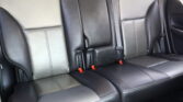 Rear car seats in black leather with light stitching and three seat positions, visible seat belts and headrests.