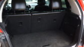 Cargo area of a red SUV with rear seats upright and black interior, viewed from the open hatch