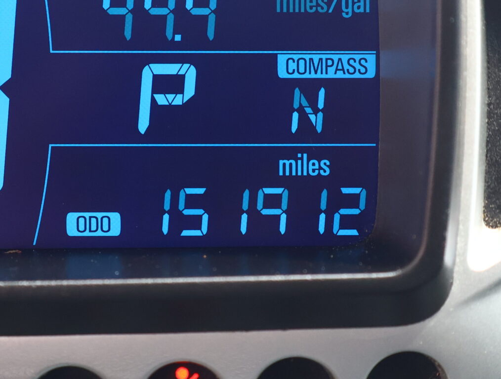 Close-up of a car's digital dashboard showing the COMPASS mode and blue numeric readout.