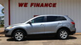 Silver SUV parked in front of a white wall with a large red 'WE FINANCE' sign.