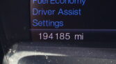 Car infotainment menu showing Trip & Fuel Economy, Driver Assist, and Settings in blue text on a dark screen