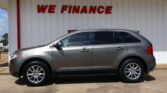 Silver SUV parked at a building with a white wall and a bold red 'WE FINANCE' sign above it.