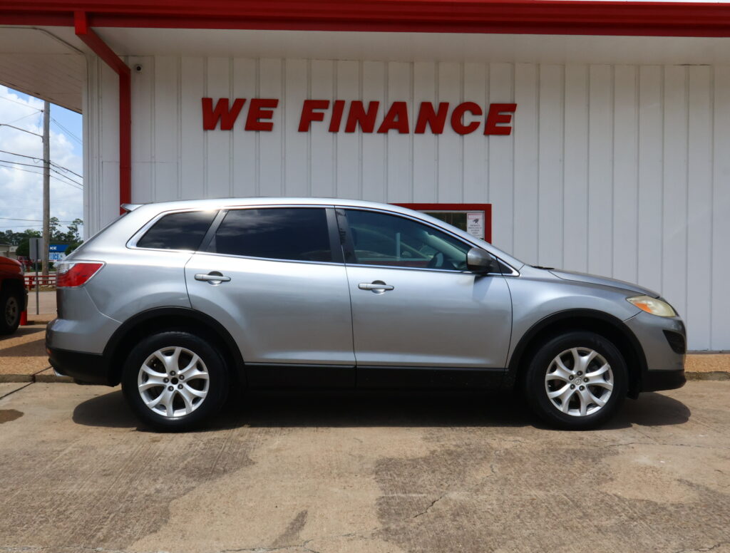Silver SUV parked in front of a white building with bold red 'WE FINANCE' sign above it.