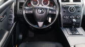 Interior car cabin centered on steering wheel with dashboard gauges and center console controls