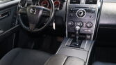 Interior of a car focused on the steering wheel and center console with black leather seats and dashboard