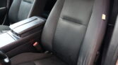 Front car seats in a dark fabric interior, with a center armrest between them and a visible seatbelt buckle.