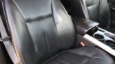 Black leather car seats with red contrast stitching and a center console with cup holders visible between the seats, front interior.