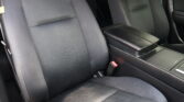 Interior of a car with black fabric seats and a center console between the seats: front and back seating visible in a dark cabin.