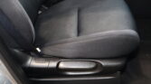 Dark car interior showing a padded fabric seat with a red-release seat belt buckle nearby on the center console area