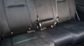 Rear car bench seat with three seating positions and visible seat belts, black fabric upholstery.