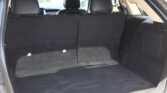Open hatchback showing a black-carpeted cargo area with the rear seats upright and headrests visible in the background.