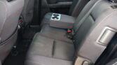 Rear car seat with a downfolded center armrest that has two cupholders, in dark fabric upholstery.