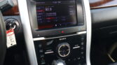 In-car infotainment screen showing radio options and preset stations, with surrounding control panel and wood trim.