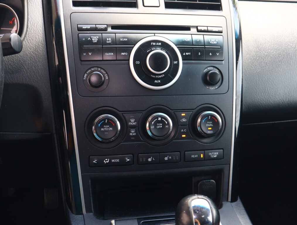 Center dashboard with car stereo controls: CD/FM/AM, volume knob, and climate dials surrounding a circular control.