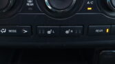 Close-up of a car climate control panel showing the center dial for temperature and surrounding buttons (front/rear defrost, A/C, heated seat indicators).