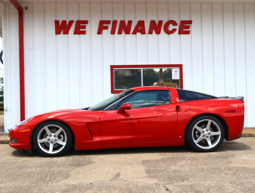 Red sports car parked in front of a white building with a bold red 'WE FINANCE' sign above.