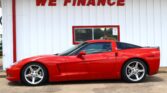 Red sports car parked in front of a white building with a bold red 'WE FINANCE' sign above.