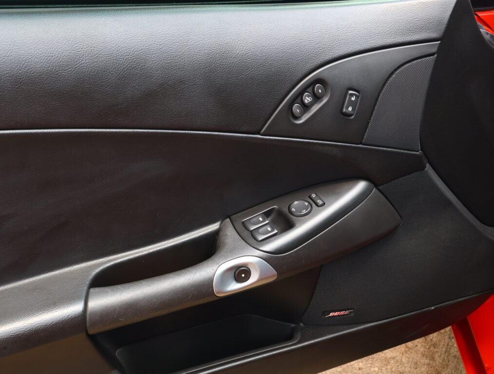 Car interior door panel showing window controls, lock switch, and a Bose speaker grille nearby.