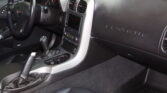 Interior view of a black Corvette cockpit with steering wheel, center console, and Corvette branding on the passenger side dash.