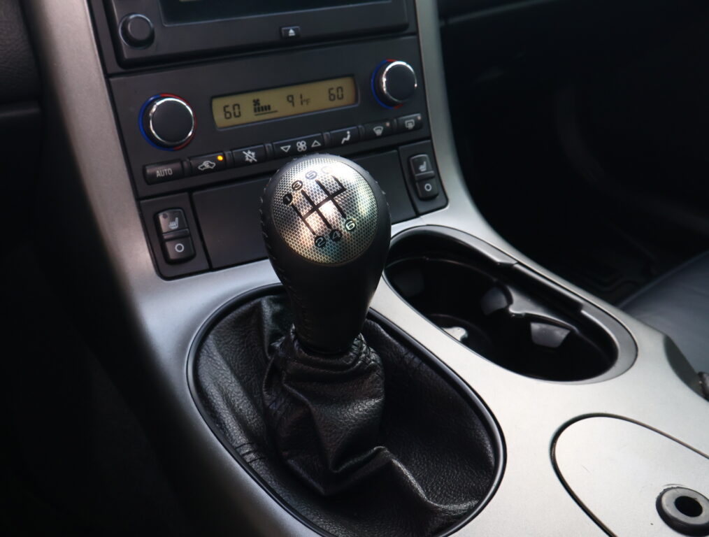 Manual gear shifter with six-speed pattern in a car interior, near climate controls and center console.