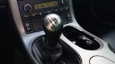 Manual gear shifter with six-speed pattern in a car interior, near climate controls and center console.