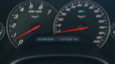 Close-up of car dashboard gauges showing RPM~6–7k and speedometer up to 200 mph, with odometer reading 117,439 miles.