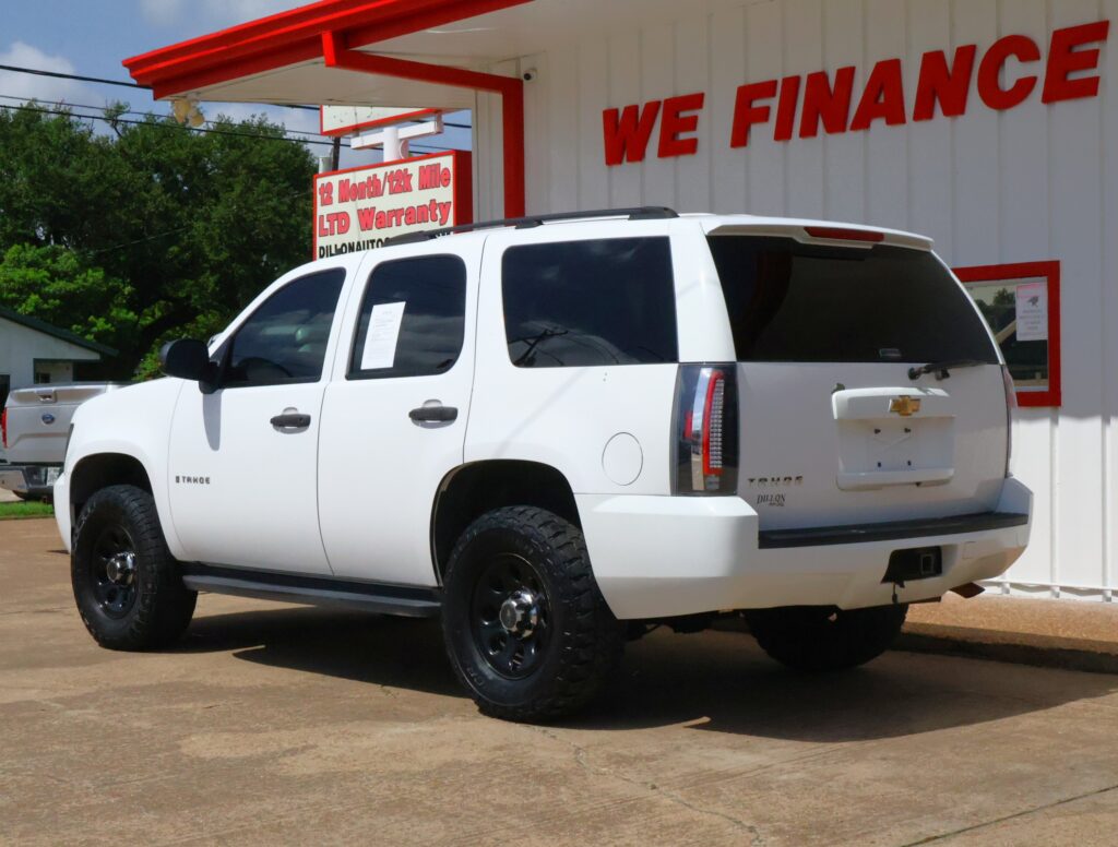 White Chevrolet Tahoe SUV parked in front of a white building with a bold red 'WE FINANCE' sign