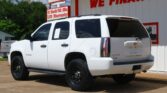 White Chevrolet Tahoe SUV parked in front of a white building with a bold red 'WE FINANCE' sign