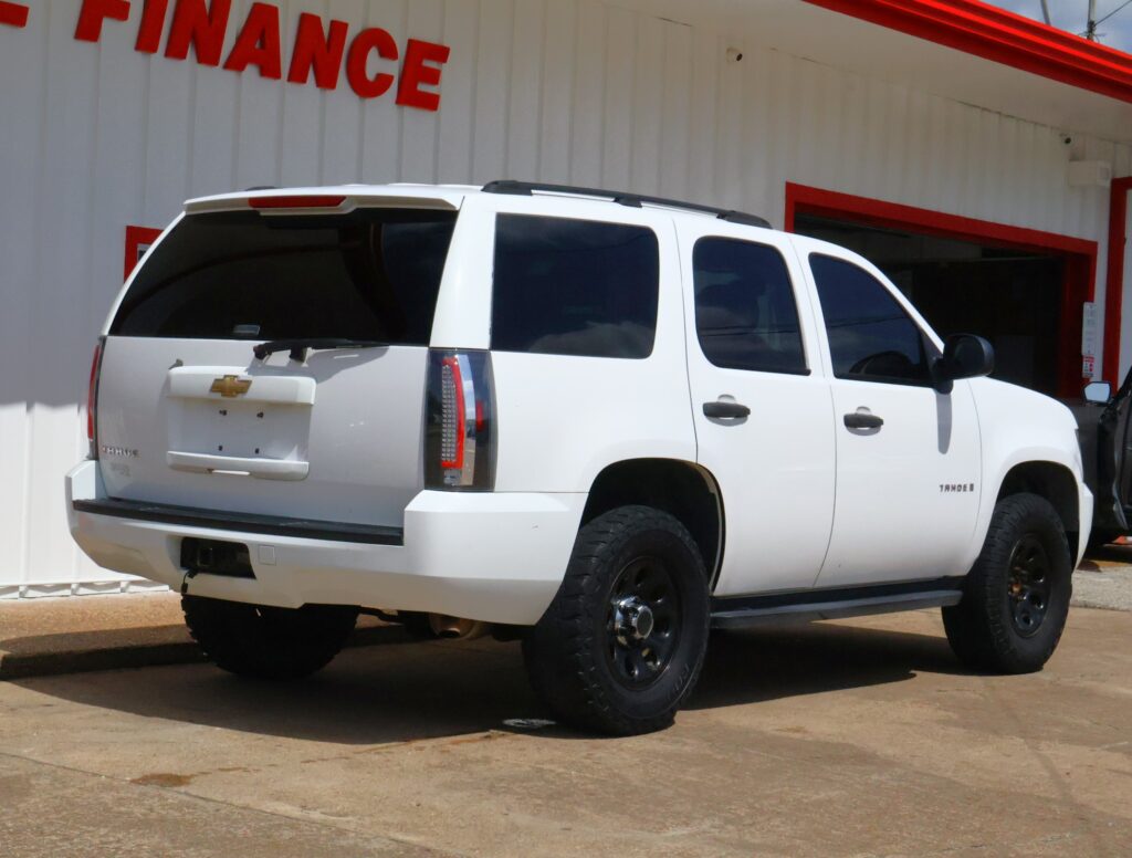 White Chevrolet Tahoe SUV parked in front of a building with a red FINANCE sign visible above it.