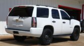White Chevrolet Tahoe SUV parked in front of a building with a red FINANCE sign visible above it.
