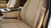 Beige car interior showing front seats, center console with two cup holders, and a side seatbelt strap visible on the right.