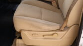 Beige car seat with a lap belt buckle visible between the seat cushion and backrest, plus side levers for seat adjustment near the bottom edge (car interior).